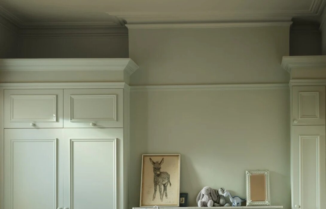 Babykamer colour-drenched in Farrow & Ball Eddy: muren, kroonlijst, plafond en kasten in één zachte tint