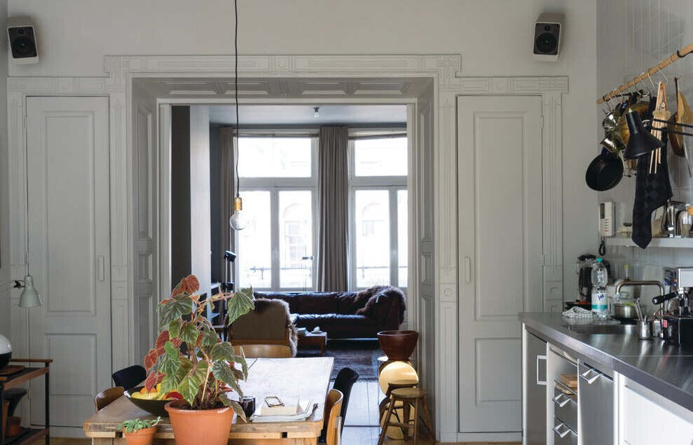 Klassiek appartement met paneeldeuren en wanden in Farrow & Ball Lamp Room Gray, met eettafel en open keuken.