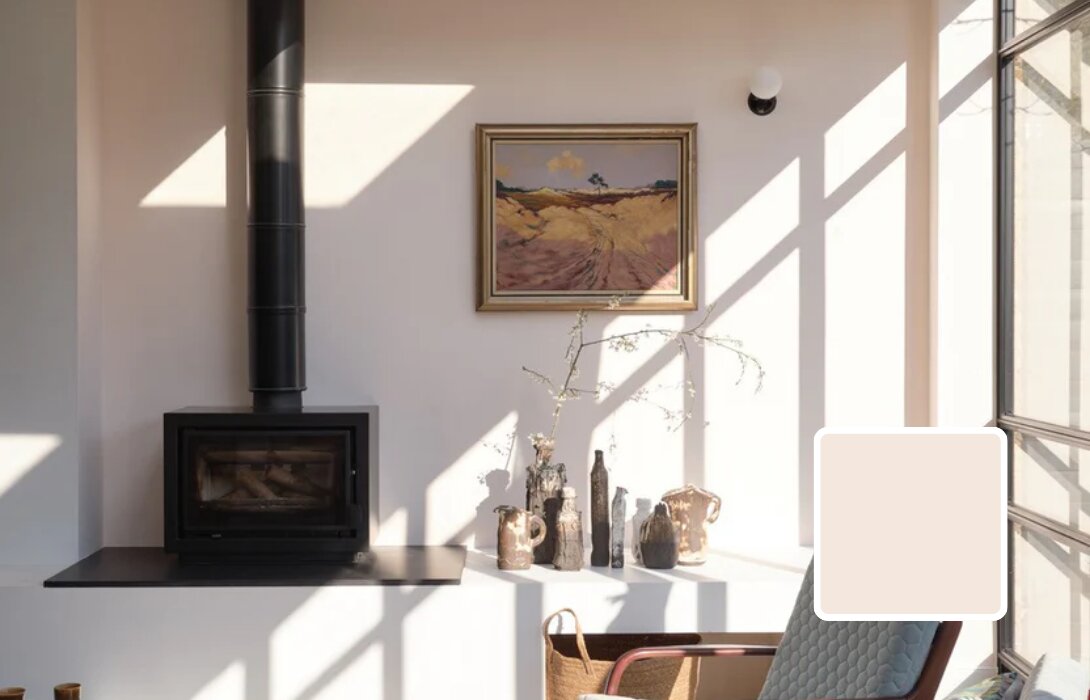 Zithoek met houtkachel en muur in Farrow & Ball Tailor Tack, een warme gedempte neutraal in de zon