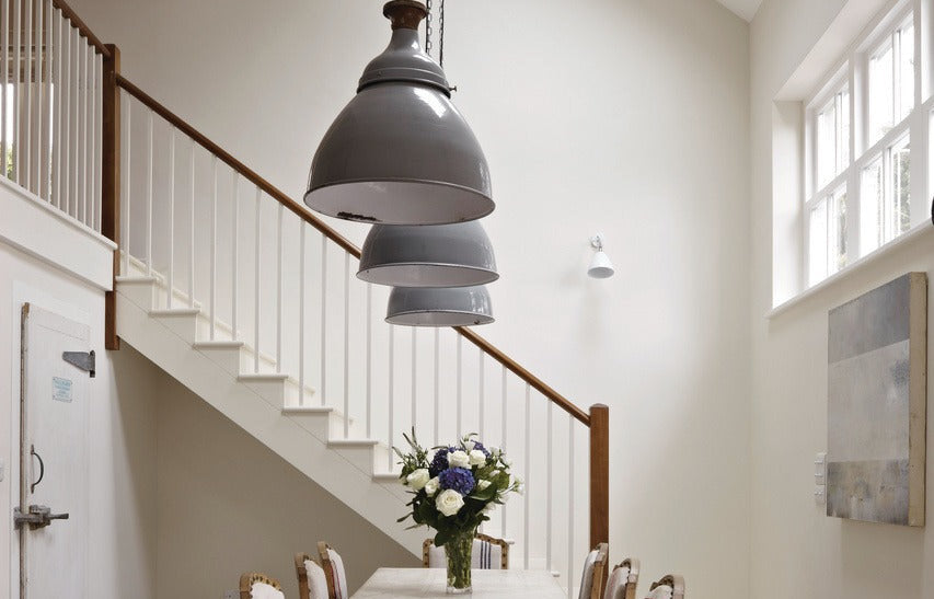 Trappenhuis met warme wanden in Farrow & Ball Hardwick White (5) en een witte trap in Slipper Satin (2004), met industriele hanglampen en een houten eettafel