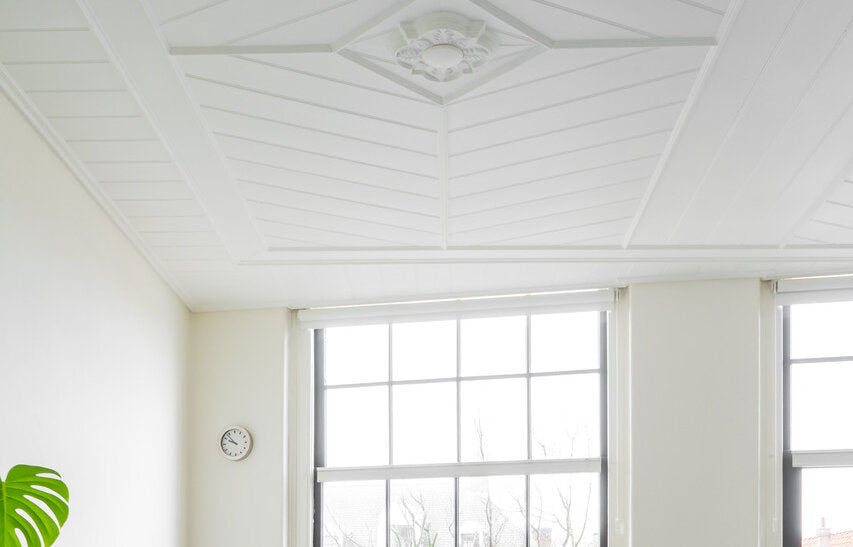 Wit plankenplafond met rozet boven witte wanden in Pure & Original Milk White (Classico), met hoge ramen en een woonkamer eronder
