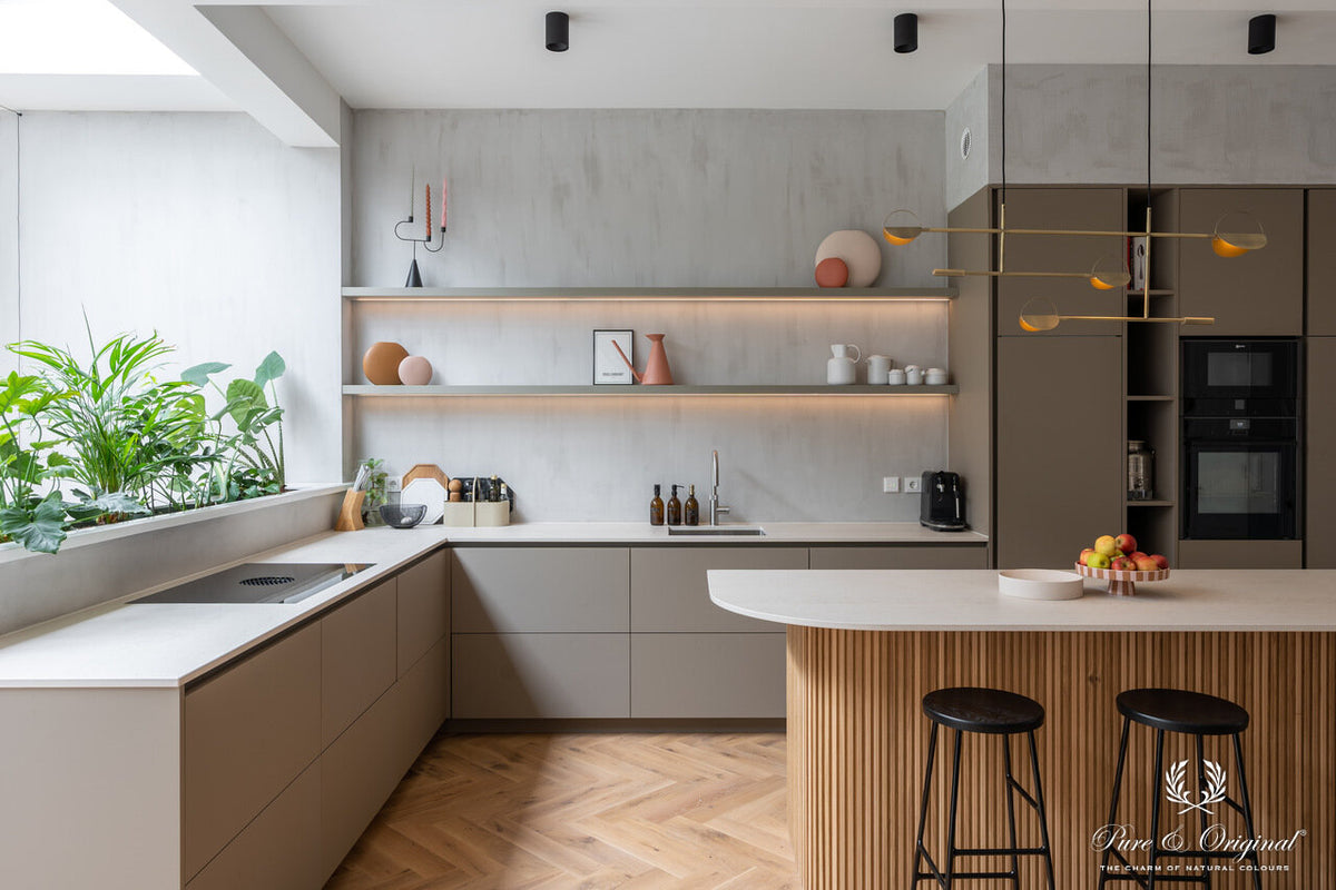 Keuken met een wand in Pure & Original Warm Grey (Fresco kalkverf), gecombineerd met greige keukenkasten, een eiken visgraatvloer en een wit werkblad.