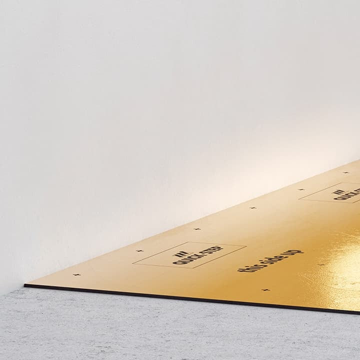 Quick-Step ondervloer met dampscherm uitgerold op een betonvloer tegen de muur