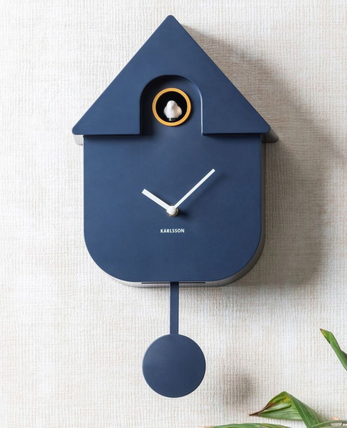 Karlsson koekoeksklok Modern Cuckoo, donkerblauw abs, sfeerfoto: aan lichte gestructureerde wand met plantenbladeren
