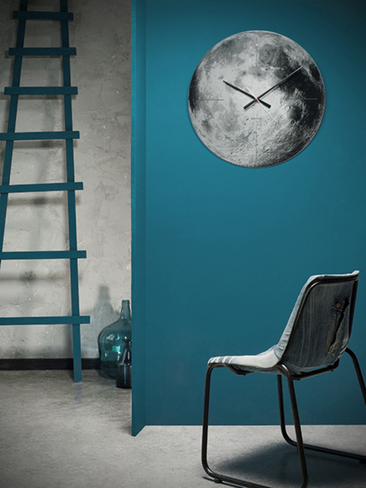 Karlsson wandklok Moon, spiegelglas, geruisloos, sfeerfoto: aan petrolblauwe wand naast ladder en stoel