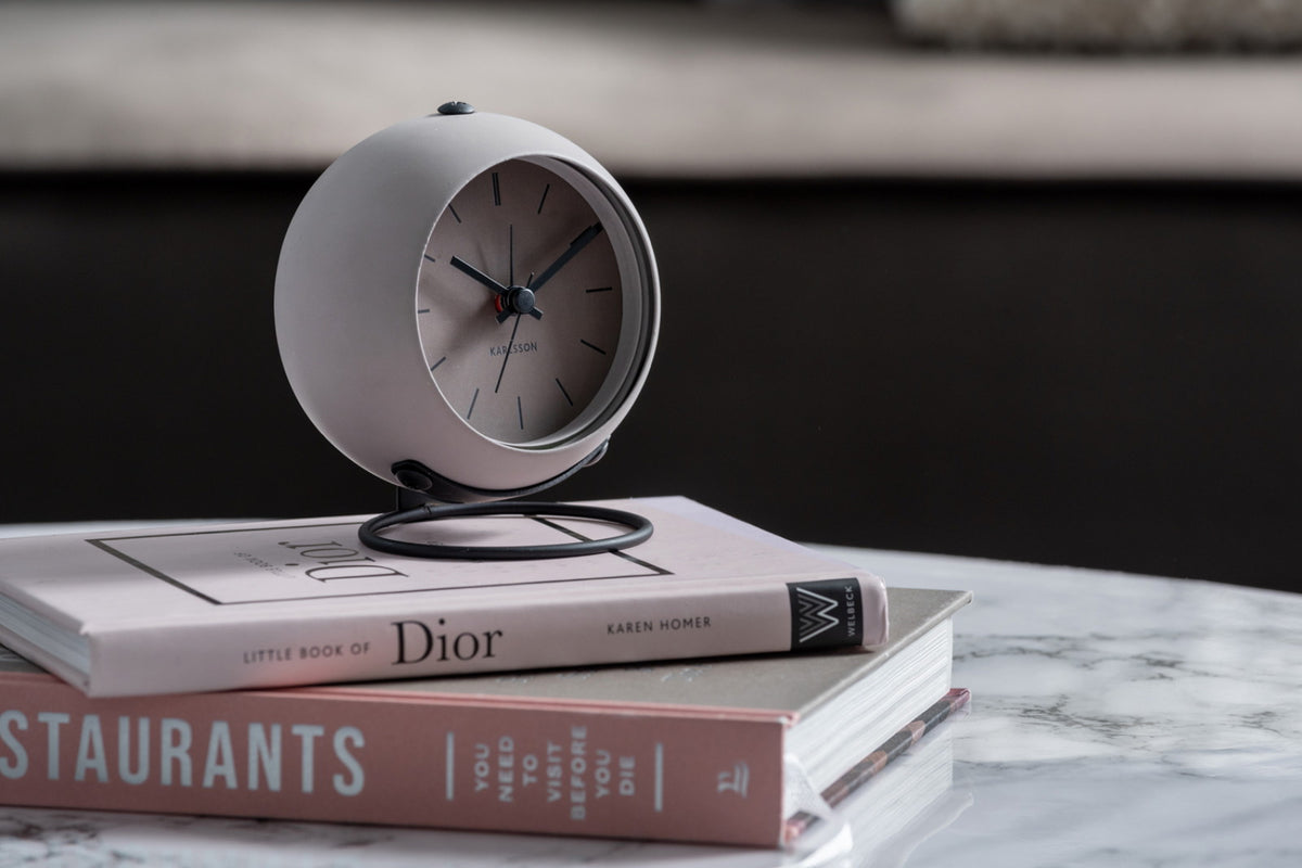 Karlsson wekker Nirvana Globe, donker warm grijs, sfeerfoto: op stapel boeken op marmeren tafel