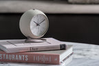 Karlsson wekker Nirvana Globe, warm grijs, sfeerfoto: op stapel boeken op marmeren tafel