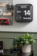 Karlsson flipklok Big Flip, zwart, sfeerfoto: aan grijsgroene wand boven bureau met plant en groene lamp