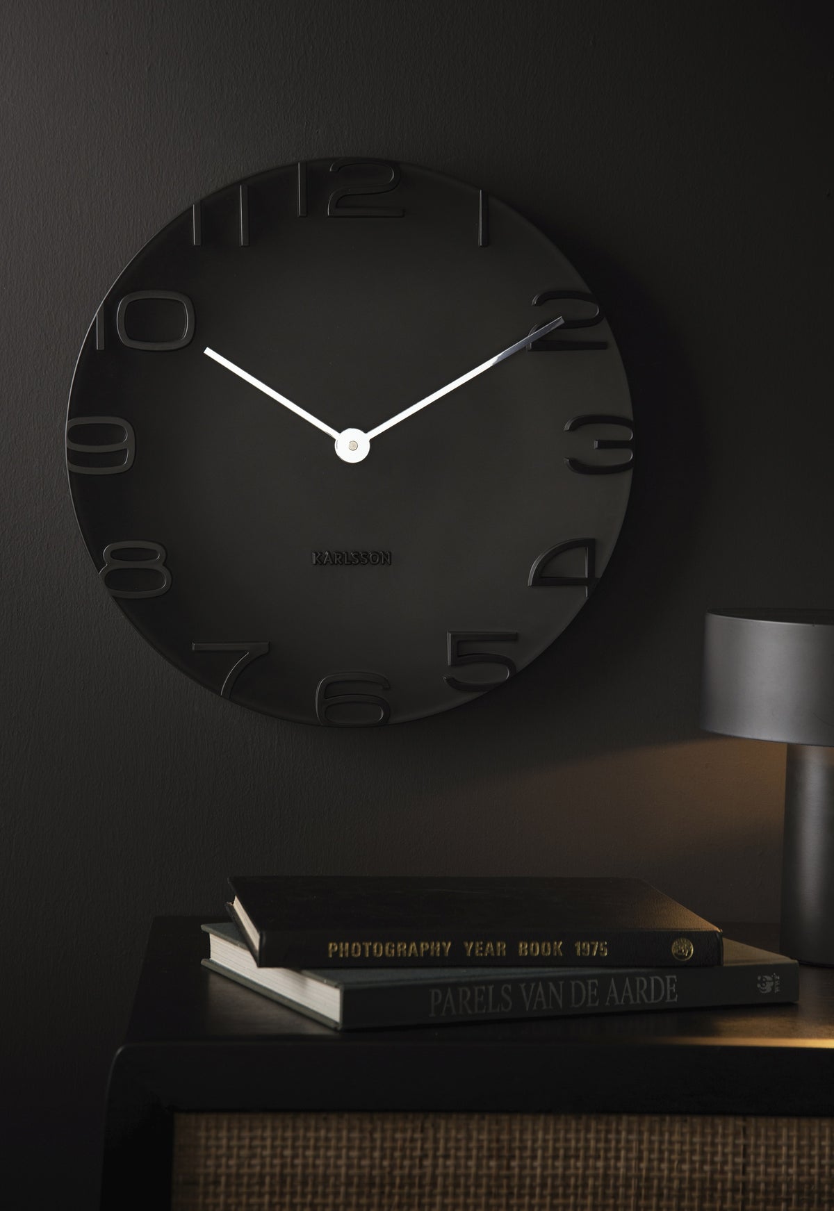 Karlsson wandklok On The Edge, zwart met chromen wijzers, sfeerfoto in interieur