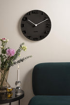 Karlsson wandklok On The Edge, zwart met chromen wijzers, sfeerfoto in interieur