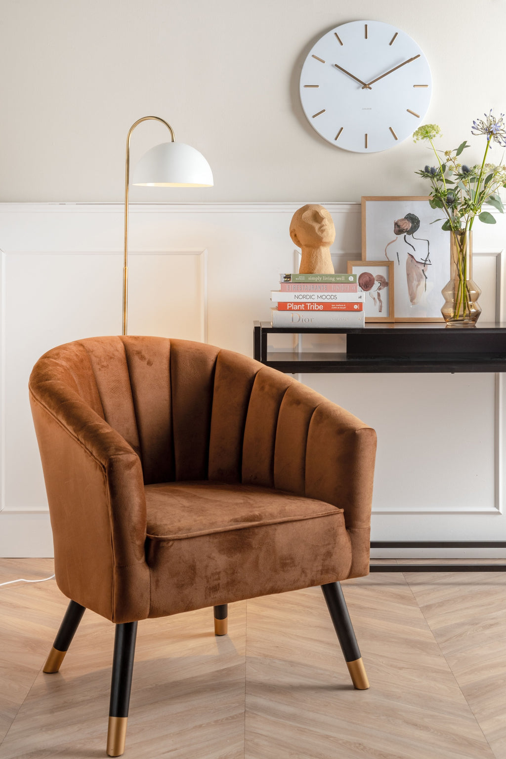 Karlsson wandklok Charm, wit, sfeerfoto: boven bruine velours fauteuil en sidetable met boeken en bloemen, witte booglamp
