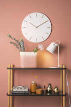 Karlsson wandklok Charm, wit, sfeerfoto: aan roze wand boven wandrek met eucalyptus, witte bureaulamp en vaasjes
