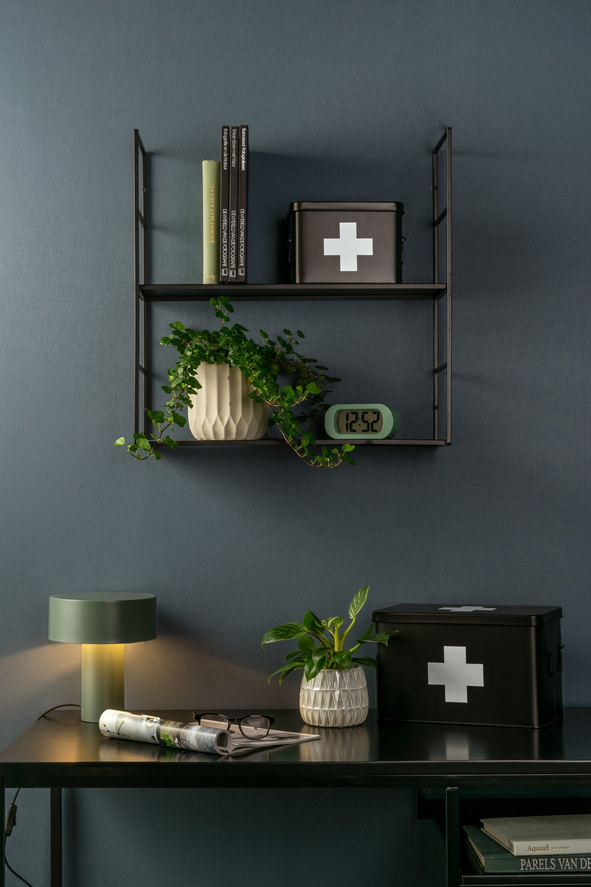 Karlsson wekker Gummy Rubberized, groen, sfeerfoto: op wandrek aan donkerblauwe wand met plant en boeken