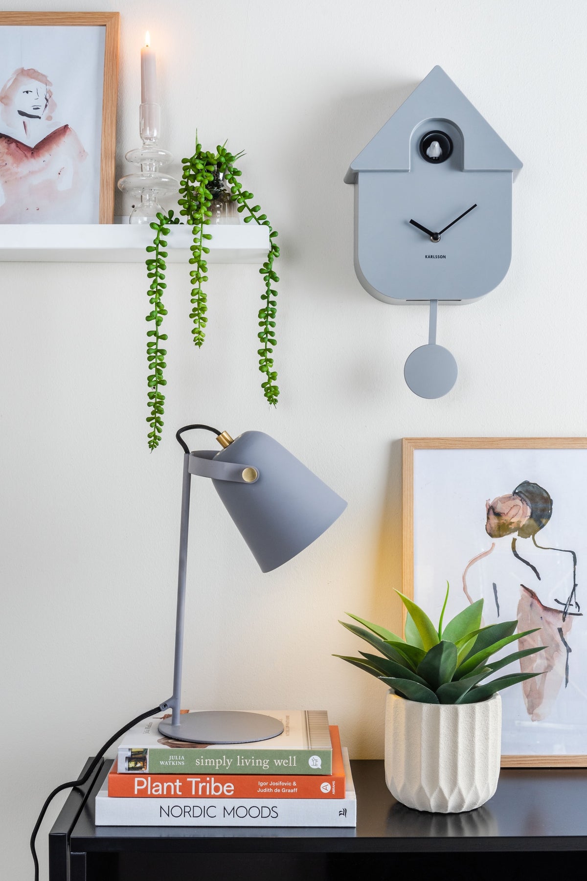 Karlsson koekoeksklok Modern Cuckoo, muisgrijs abs, sfeerfoto: aan lichte wand naast bureaulamp, boeken, plant en posters
