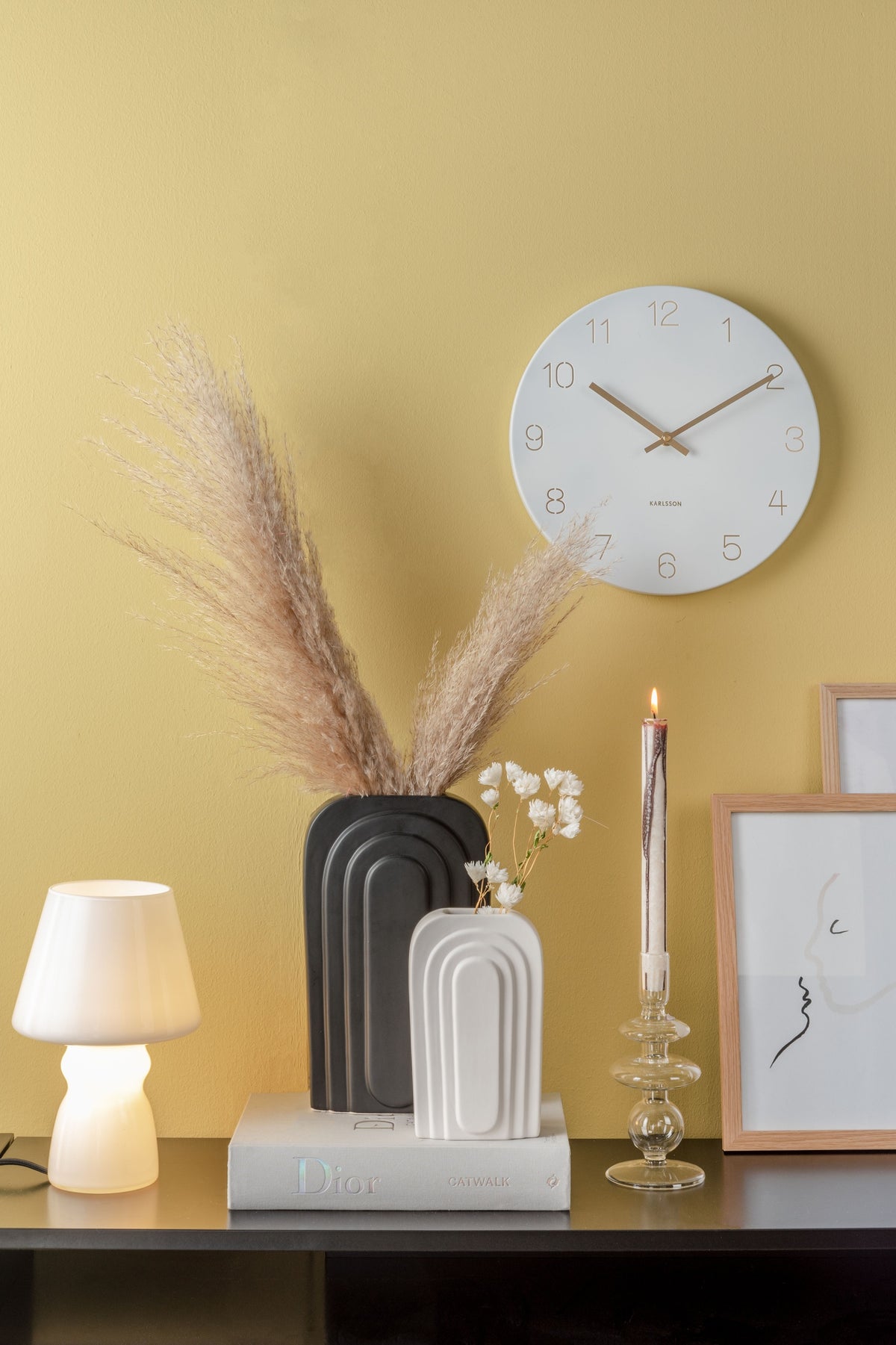 Karlsson wandklok Charm Small, gegraveerde cijfers, wit, sfeerfoto: aan gele wand boven zwarte sidetable met vazen