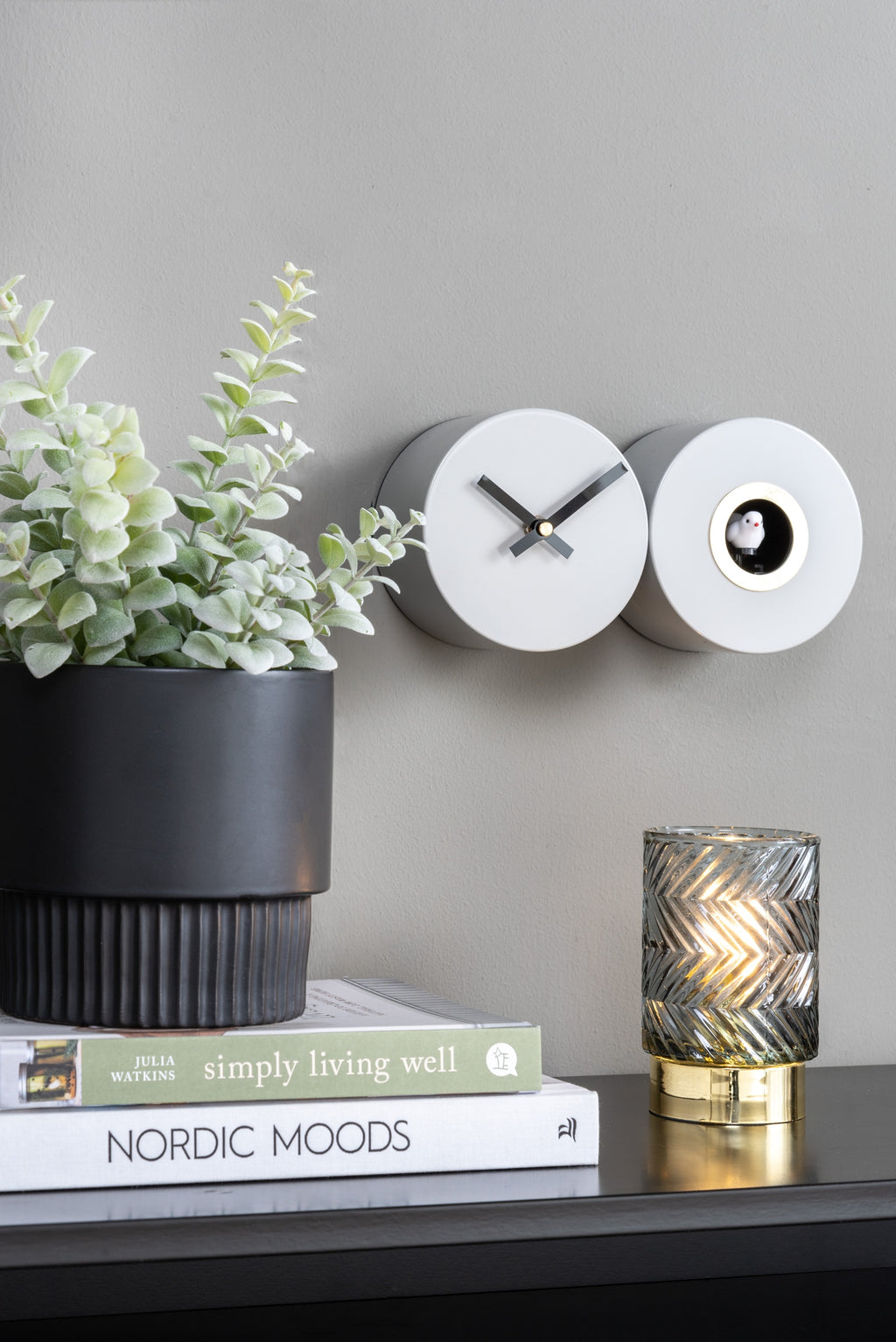 Karlsson koekoeksklok Duo Cuckoo, mat jungle groen, sfeerfoto: aan grijze wand naast plant, boeken en lamp