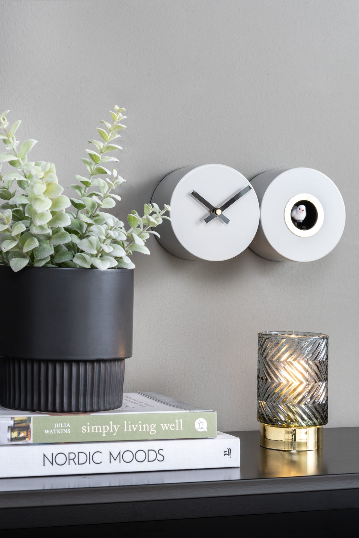 Karlsson koekoeksklok Duo Cuckoo, mat jungle groen, sfeerfoto: aan grijze wand naast plant, boeken en lamp
