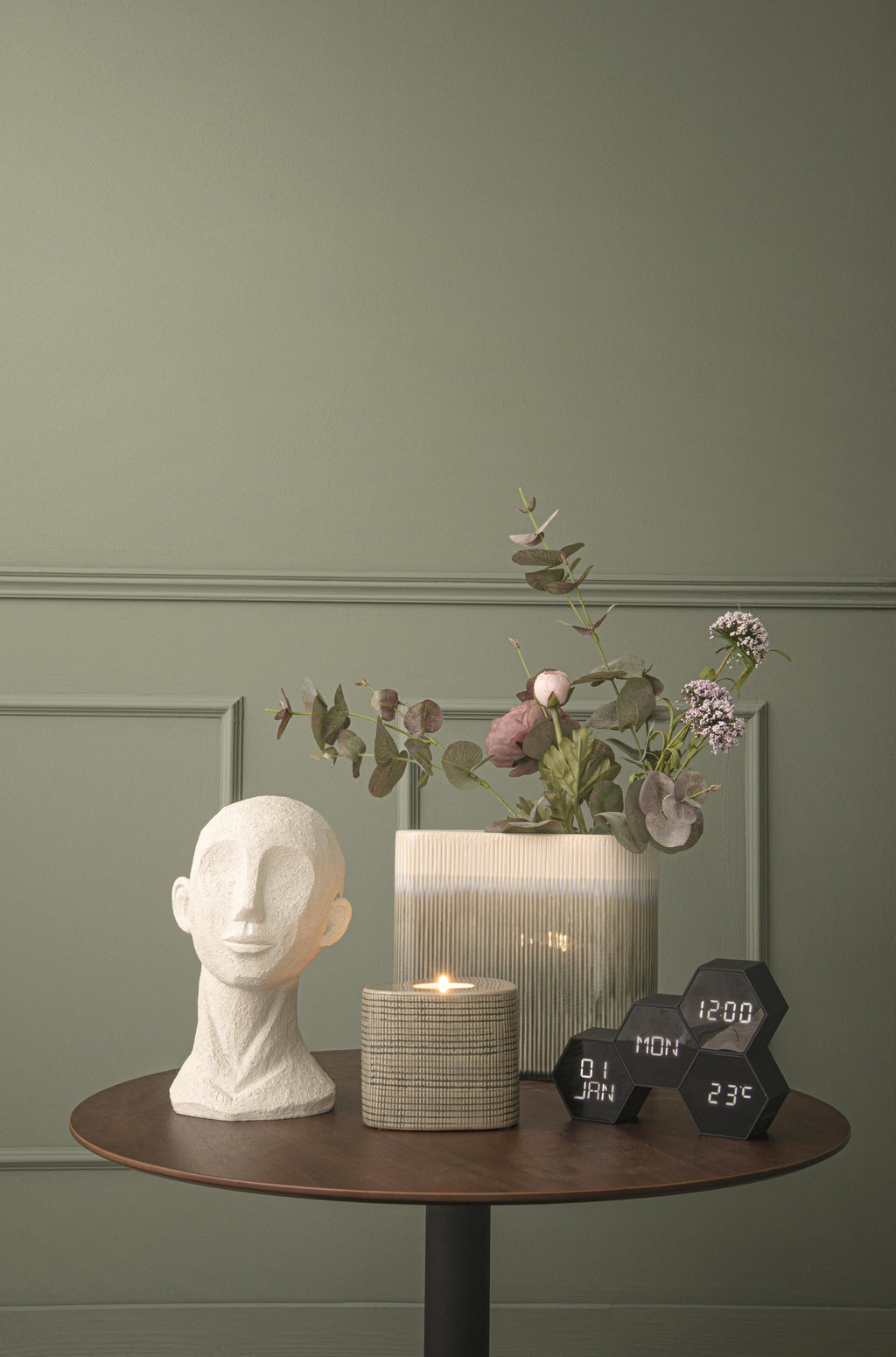Karlsson wekker Six In The Mix, zwart rubber, sfeerfoto: op ronde tafel naast hoofdbeeld, kaars en bloemen
