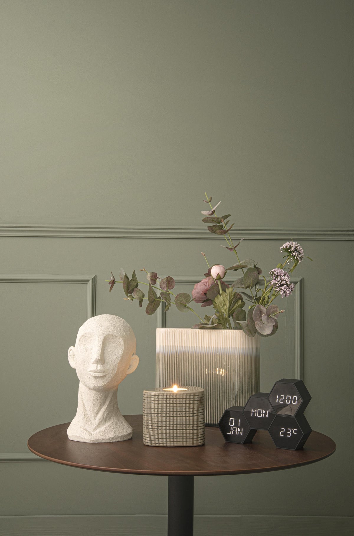 Karlsson wekker Six In The Mix, zwart rubber, sfeerfoto: op ronde tafel naast hoofdbeeld, kaars en bloemen