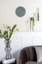 Karlsson wandklok Charm Small, groen, sfeerfoto: aan crème wand boven wandplank met hangplant en kandelaars