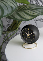 Karlsson wekker Globe Armando Breeveld, zwart, sfeerfoto: op wit tafeltje voor plant en botanisch behang