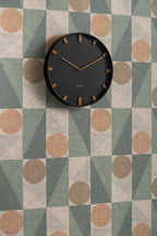 Karlsson wandklok Grace, zwart, sfeerfoto: aan wand met geometrisch behang in groen, beige en terracotta