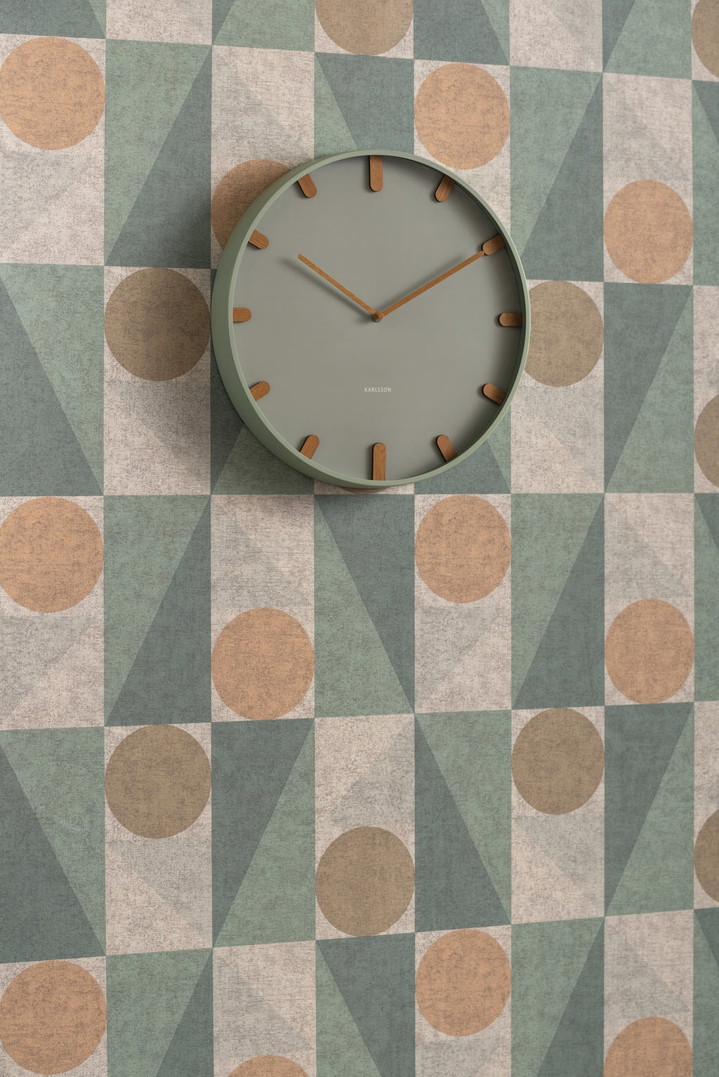 Karlsson wandklok Grace, groen, sfeerfoto: aan wand met geometrisch behang in groen, beige en terracotta