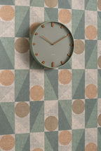 Karlsson wandklok Grace, groen, sfeerfoto: aan wand met geometrisch behang in groen, beige en terracotta