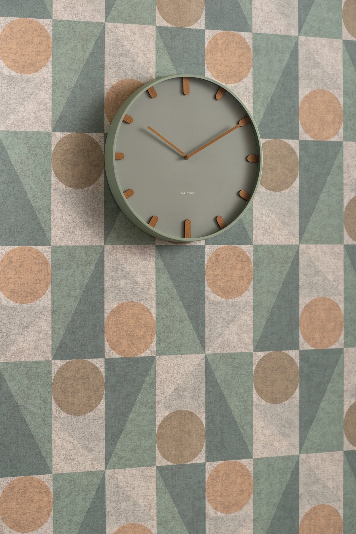 Karlsson wandklok Grace, groen, sfeerfoto: aan wand met geometrisch behang in groen, beige en terracotta