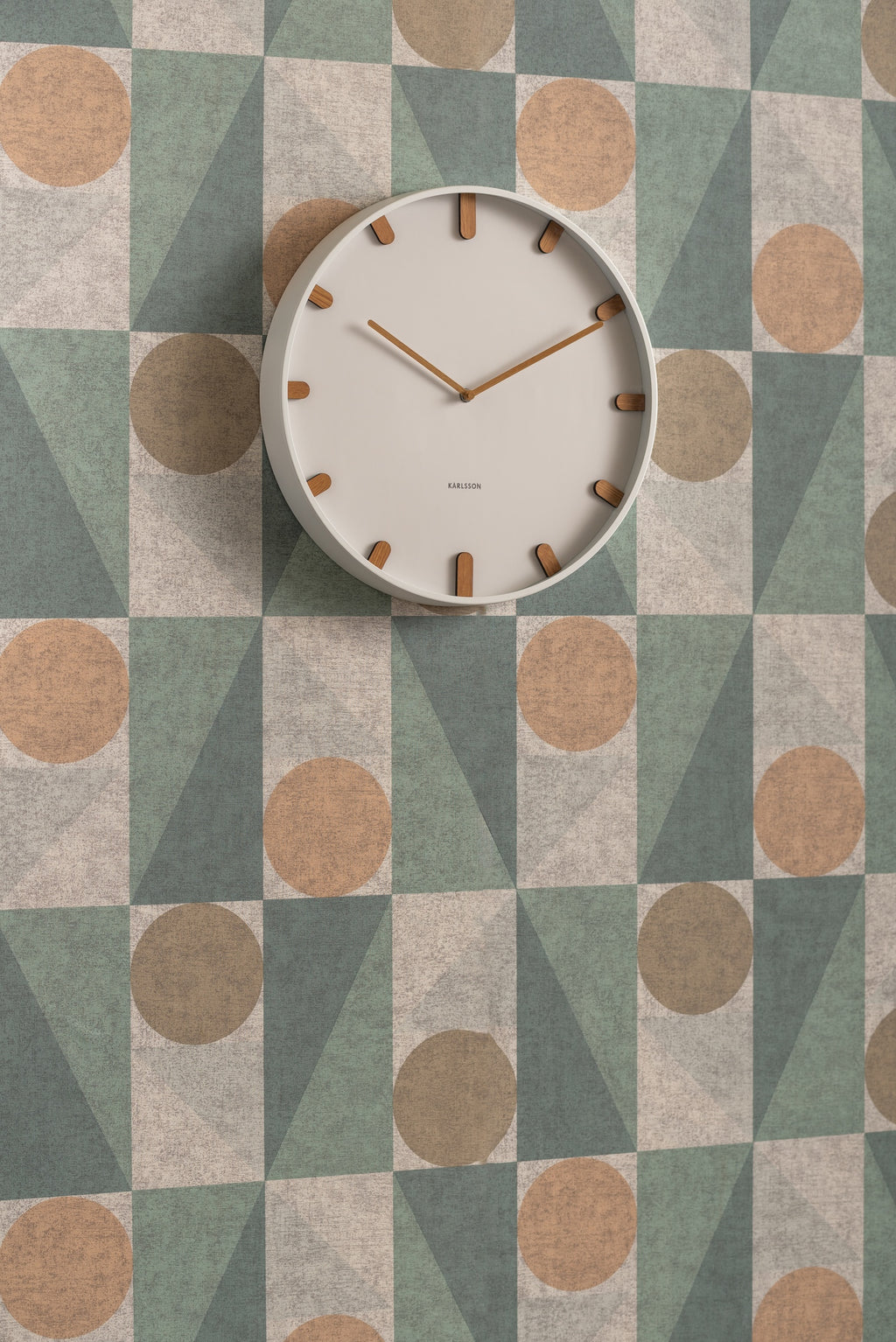 Karlsson wandklok Grace, wit, sfeerfoto: aan wand met geometrisch behang in groen, beige en terracotta