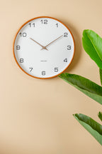 Karlsson wandklok Acento, wit, sfeerfoto: aan beige muur naast groene plant