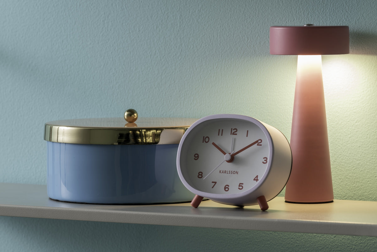 Karlsson wekker Cheeky Oval, zachtpaars, sfeerfoto: op plank naast blauwe opbergdoos en roze lamp