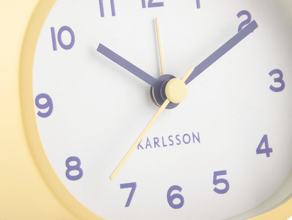 Karlsson wekker Cheeky Oval, zachtgeel, detail: wijzerplaat met paarse cijfers en Karlsson-logo
