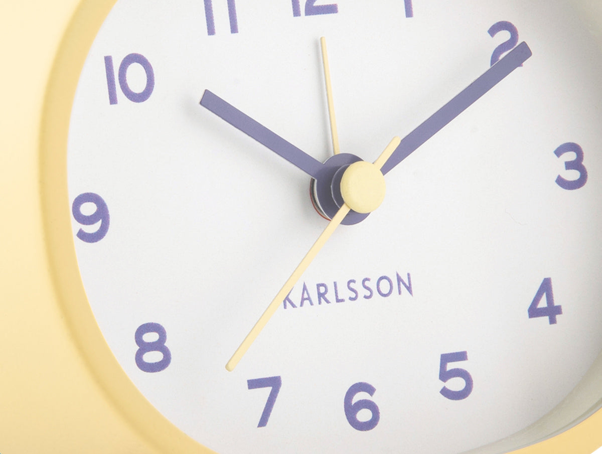 Karlsson wekker Cheeky Oval, zachtgeel, detail: wijzerplaat met paarse cijfers en Karlsson-logo