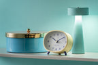 Karlsson wekker Cheeky Oval, zachtgeel, sfeerfoto: op plank naast blauwe opbergdoos en mintgroene lamp
