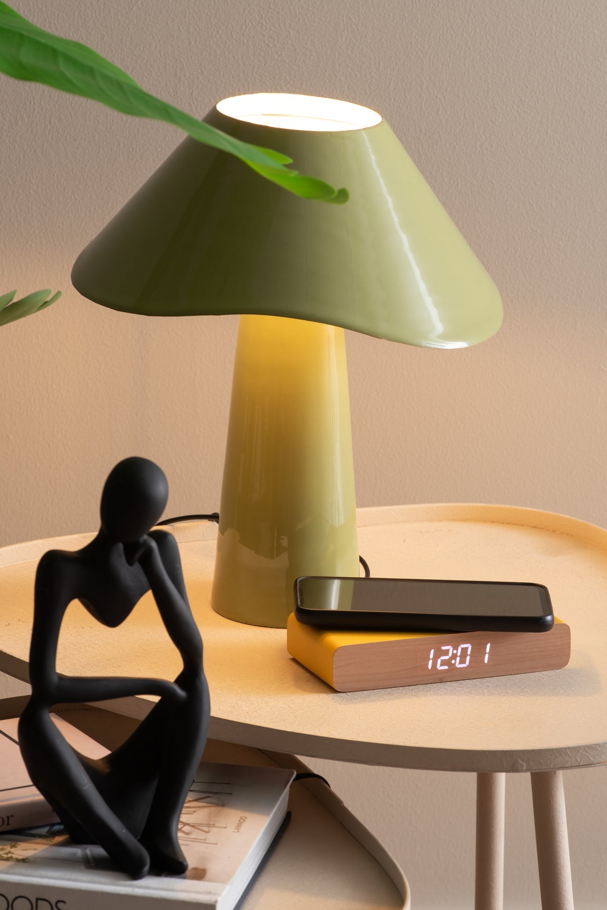 Karlsson wekker Retro Flat LED, geel, sfeerfoto: op bijzettafel onder groene lamp, telefoon ligt erop, display 12:01