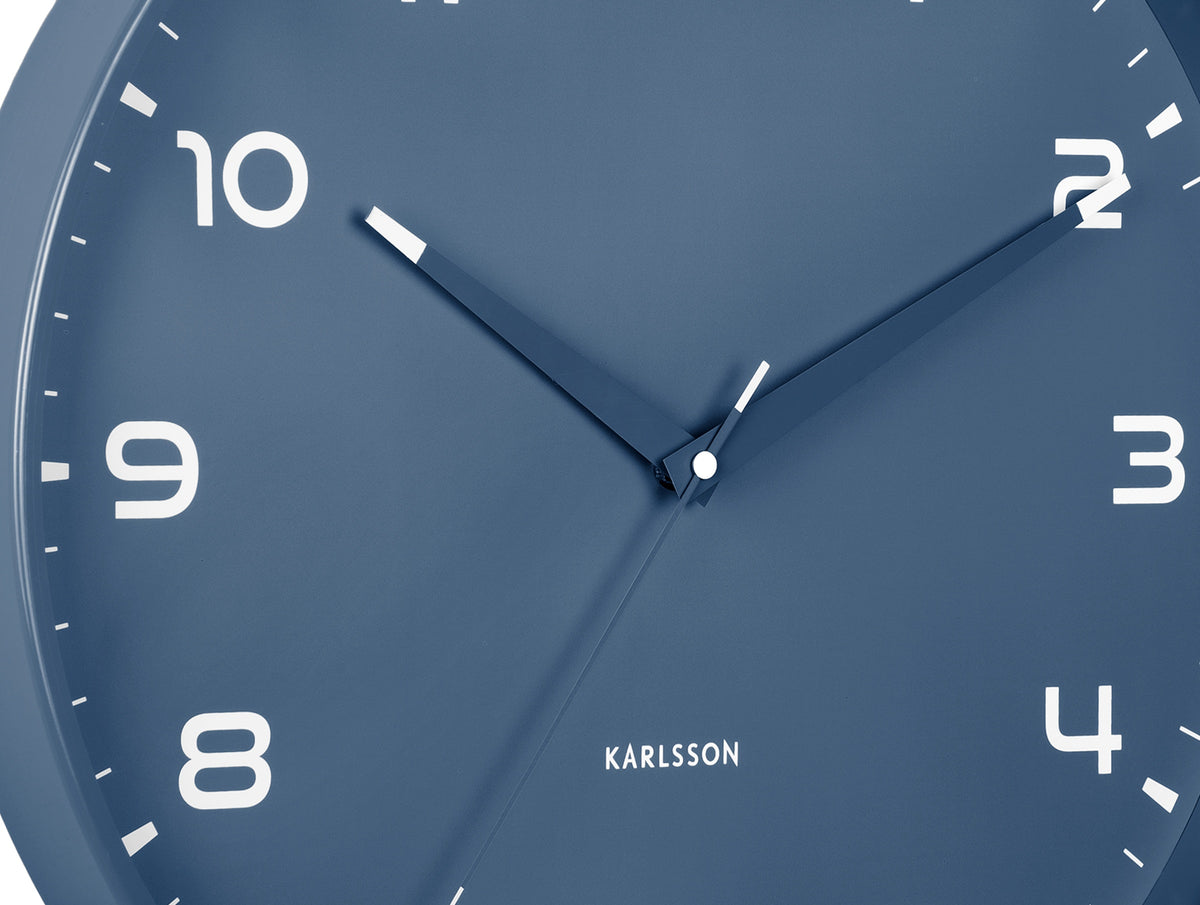 Karlsson wandklok Orgullo, klassiek blauw, detail: wijzerplaat met witte cijfers, lichtgevende wijzers en Karlsson-logo