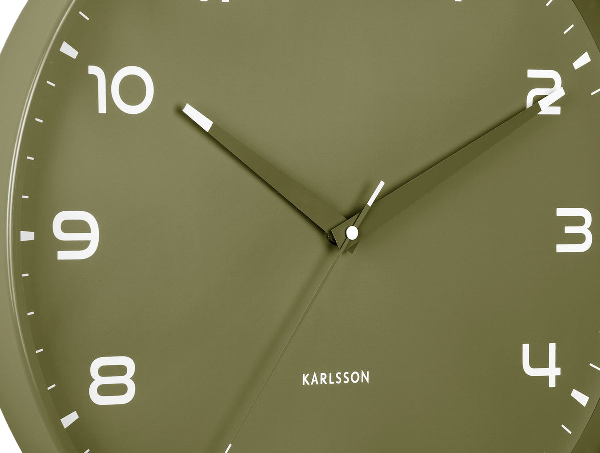 Karlsson wandklok Orgullo, legergroen, detail: wijzerplaat met witte cijfers, lichtgevende wijzers en Karlsson-logo