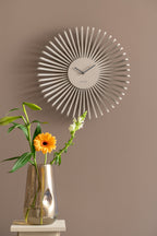 Karlsson wandklok Polo, grijs, sfeerfoto: aan taupe muur boven glazen vaas met oranje gerbera