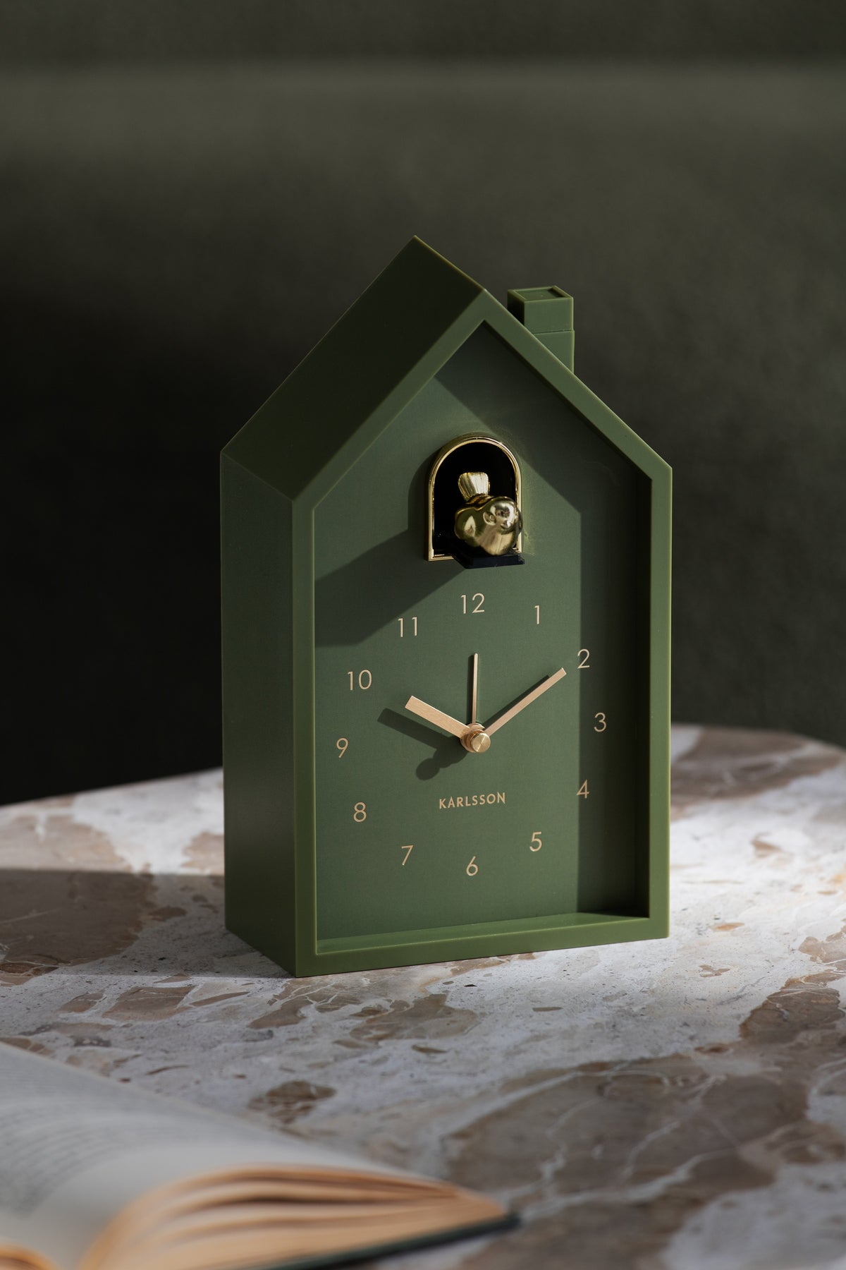 Karlsson wekker Modern Cuckoo Oro, groen, sfeerfoto: staand op marmeren tafel naast open boek