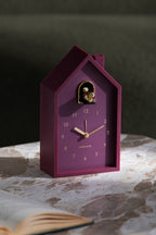 Karlsson wekker Modern Cuckoo Oro, paars, sfeerfoto: staand op marmeren tafel naast open boek