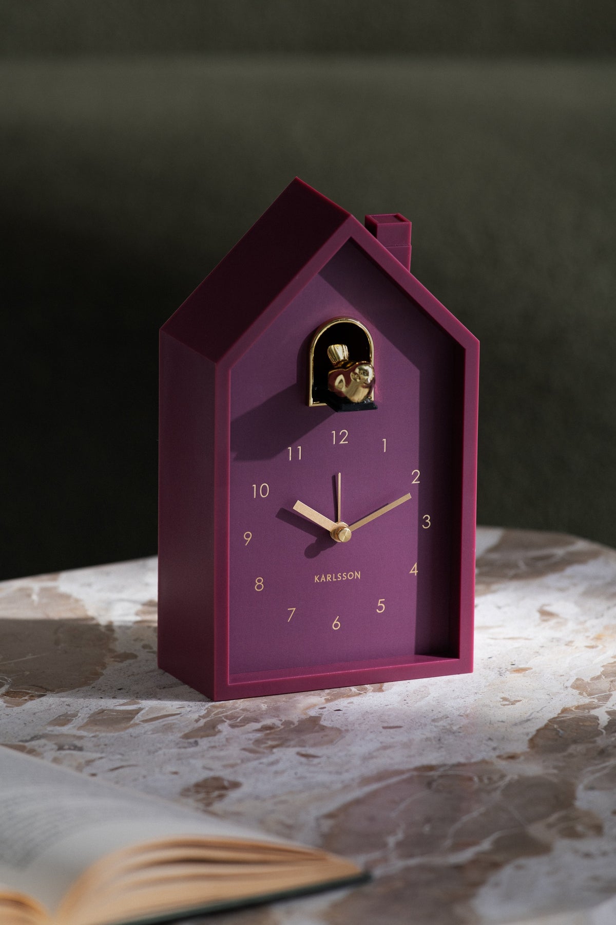 Karlsson wekker Modern Cuckoo Oro, paars, sfeerfoto: staand op marmeren tafel naast open boek
