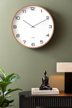Karlsson wandklok Delicado Large, wit, sfeerfoto: aan groene muur boven zwart dressoir met beeldje