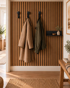 Hal met houten wandpaneel, drie zwarte kapstokhaken met jassen en een zwarte wandplank