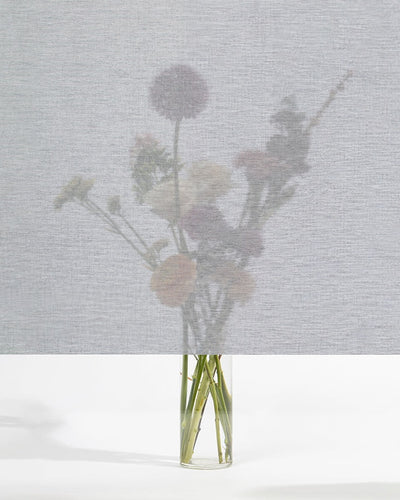 Squid raamtextiel Ash (lichtgrijs): transparant textiel voor het raam, met een boeket bloemen zichtbaar erachter