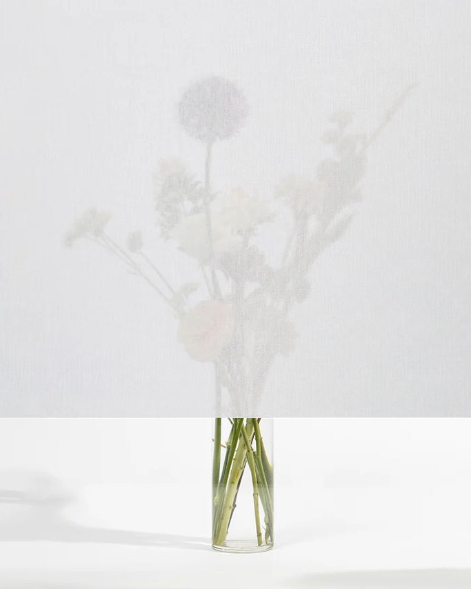 Squid raamtextiel Chalk (wit): transparant textiel voor het raam, met een boeket bloemen zichtbaar erachter