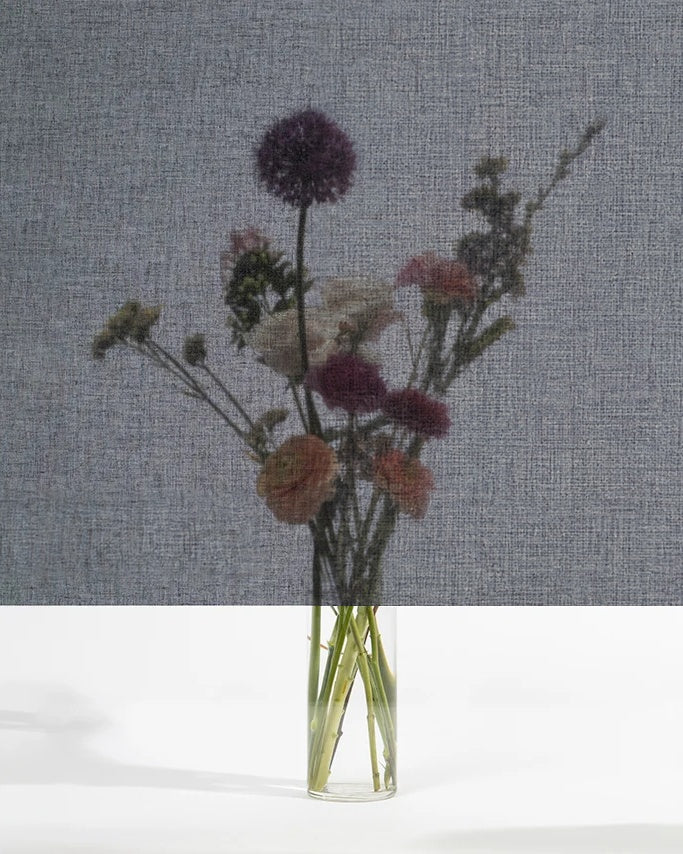 Squid raamtextiel Coal (zwart): transparant textiel voor het raam, met een boeket bloemen zichtbaar erachter