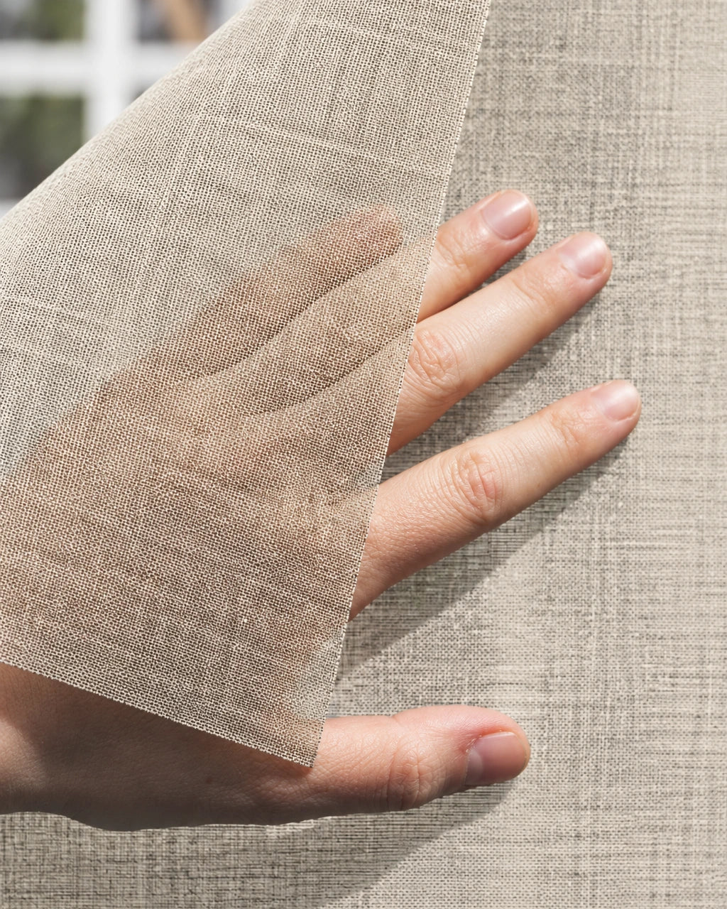 Squid raamtextiel op maat Oak - Beige: hand tilt een hoek van het doorzichtige raamtextiel op voor een raam